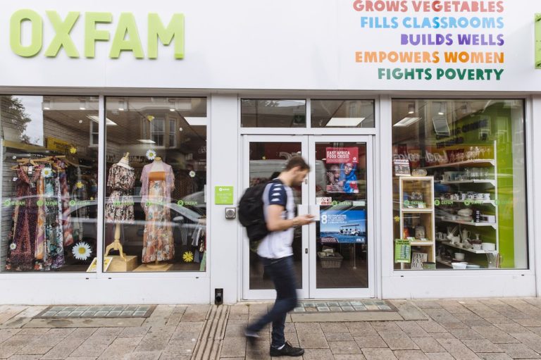 Man walking in front of an Oxfam Store in Oban